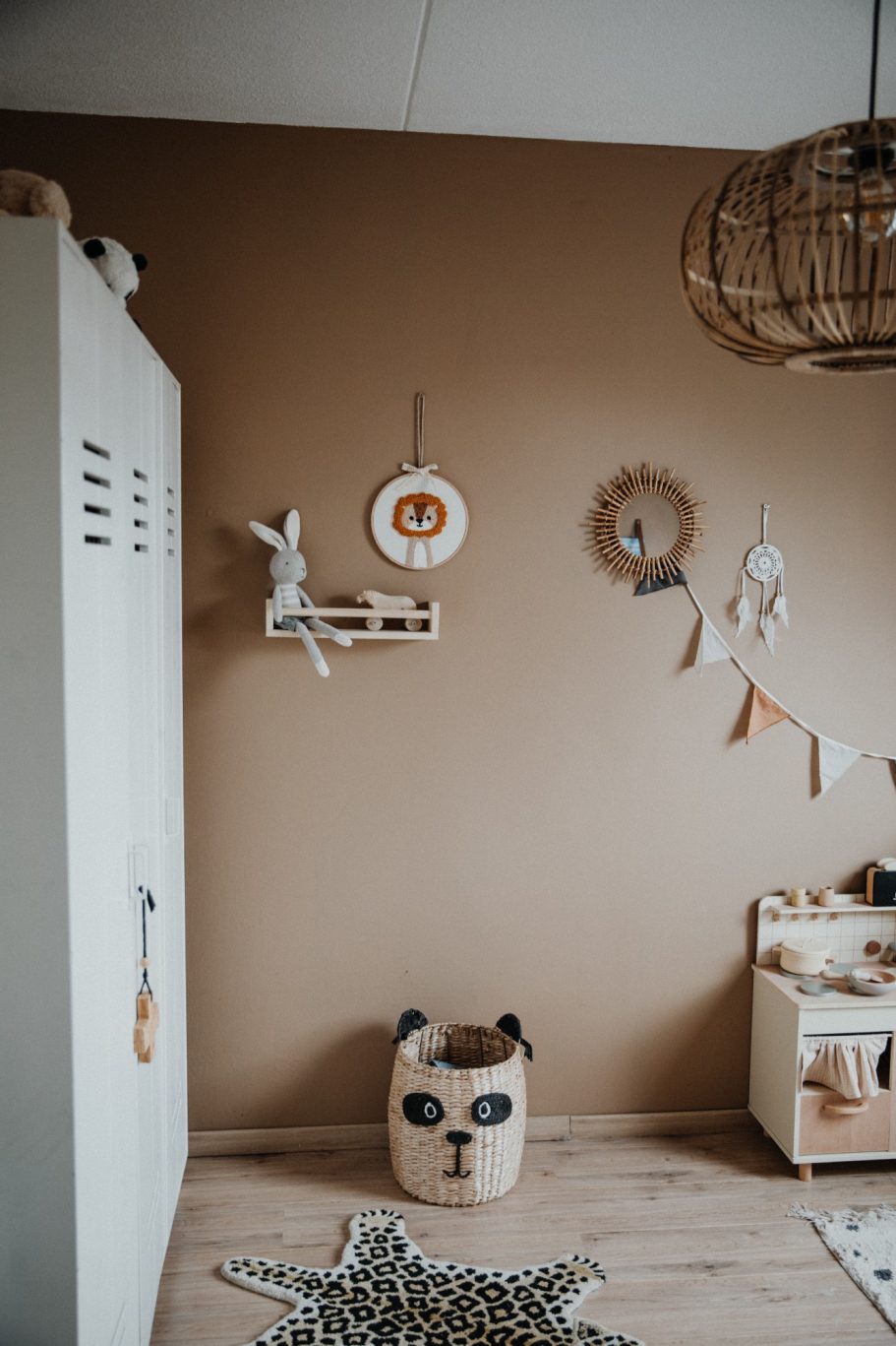Speelse kinderkamer met een bruine muur, wanddecoraties en een diervormig opbergrek.