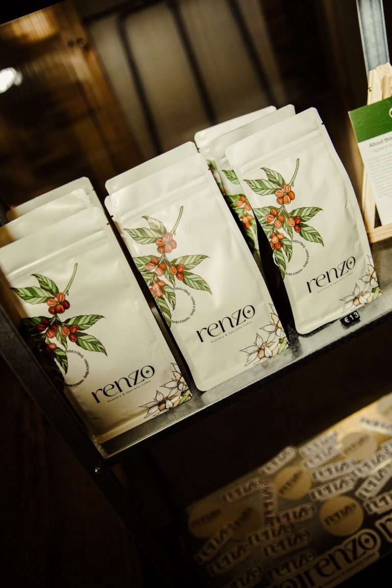 Witte zakken met bloemenillustraties, op een rek in een winkel.