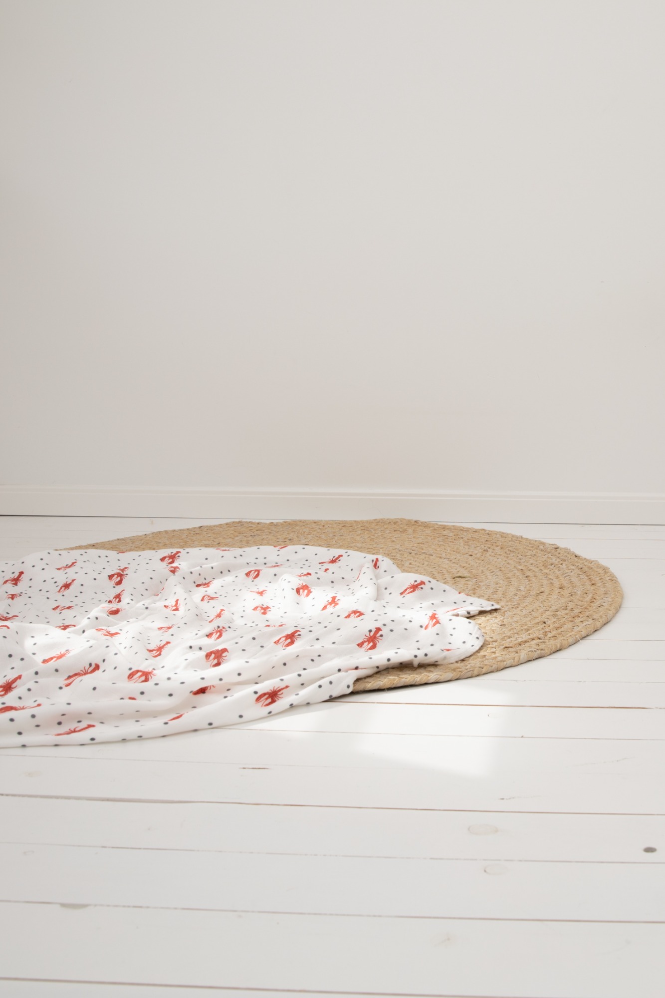 Witte deken met rode stippen op een jute mat, op een lichte houten vloer.
