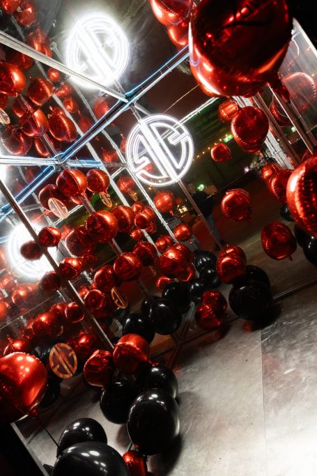 Rode en zwarte bollen in een reflecterende omgeving met neonlichten.