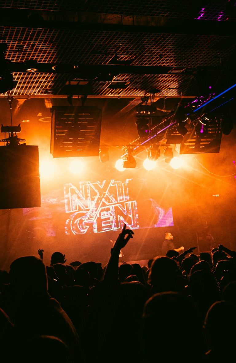 Een drukke club met een lichtshow en mensen die dansen op de muziek.