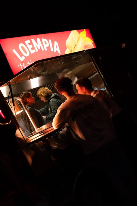 Voedseltruck met mensen die bestellen en genieten van loempia's.