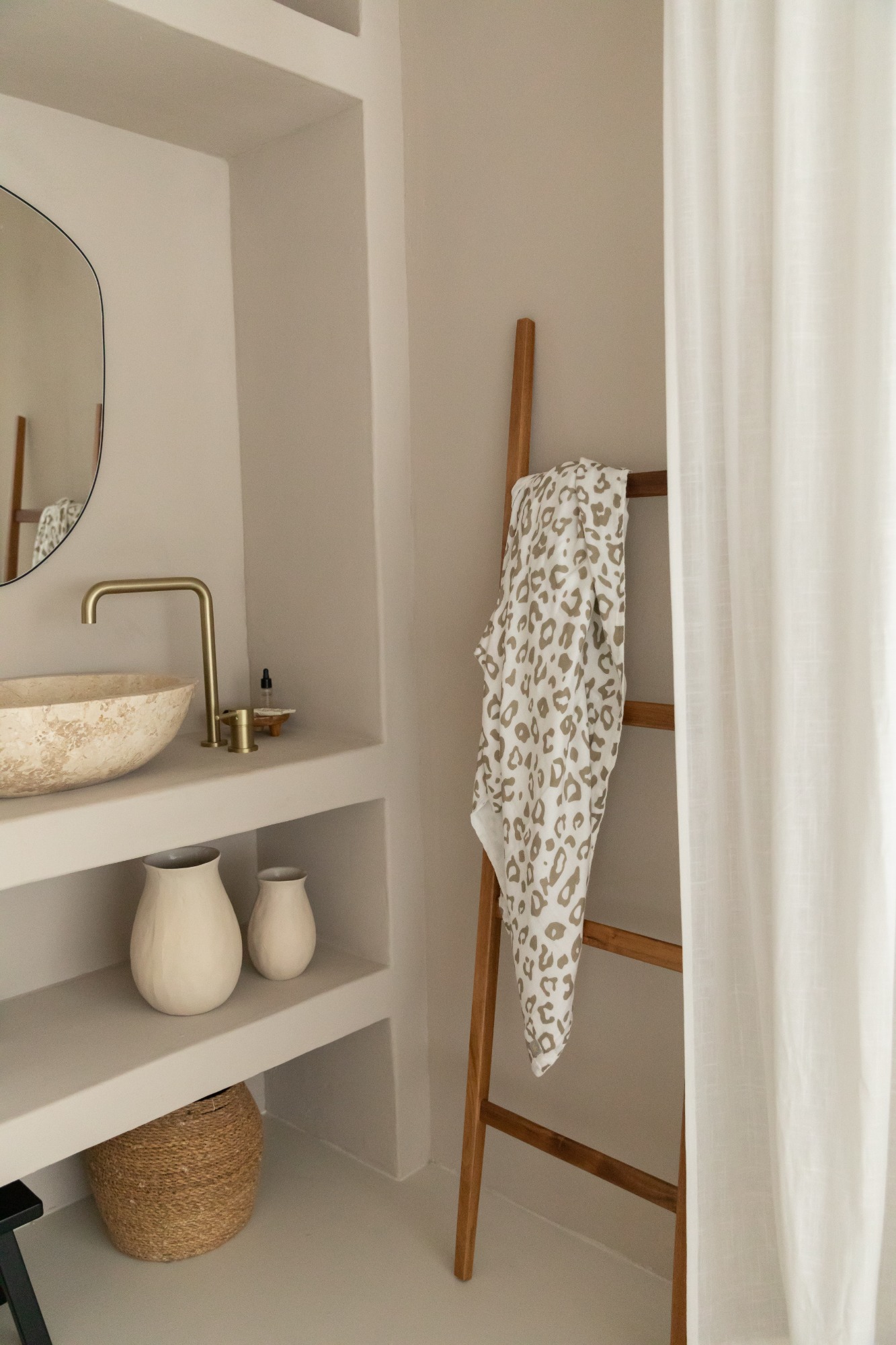 Moderne badkamer met wastafel, decoratieve flessen en een houten ladder met handdoek.