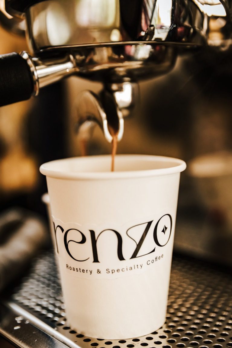 Witte koffiekop met het logo van Renzo, gevuld met vers gezette koffie.