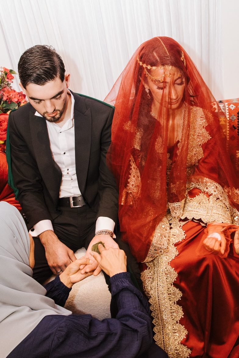 Een bruid met een rode sluier en een bruidegom tijdens een traditionele ceremonie.