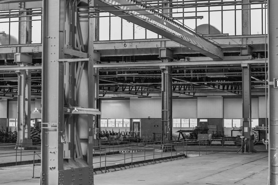 Lege industriële ruimte met hoge plafonds en grote vensters.