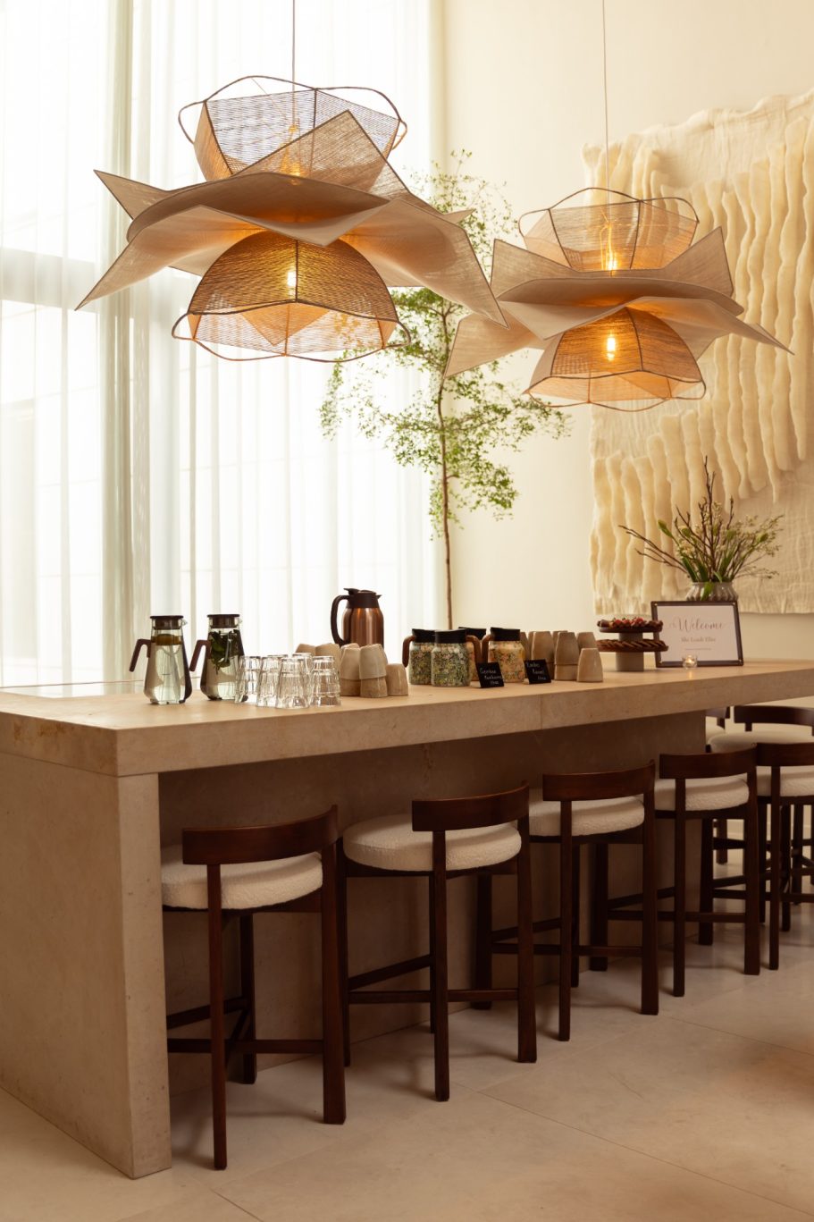 Moderne bar met houten stoelen en decoratieve hanglampen in een lichte ruimte.