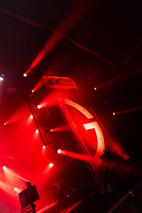 Rood verlichte podium met een groot, opvallend logo in de vorm van een letter G.